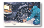 A person in a blue coat cleaning a car tire
Description automatically generated